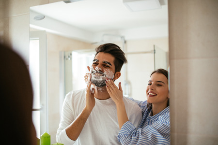 Portrait of a young couple having fun with shaving foam in the bathroom.の写真素材