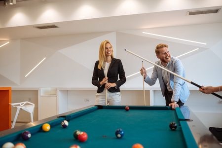 Portrait of business people playing pool table together.の写真素材