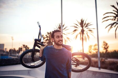 Portrait of a handsome young man carrying bicycle outdoors.の写真素材