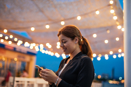 Close up portrait of a young woman using mobile phone outdoors.の写真素材