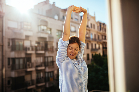 Portrait of a beautiful woman stretching on the balcony.の写真素材