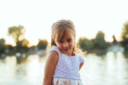 Close up portrait of a smiling girl standing near the river.の写真素材