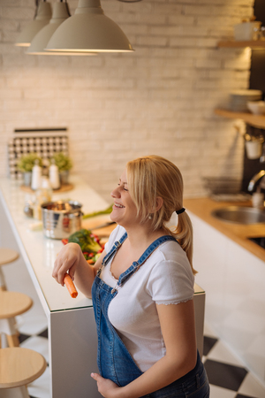 Shot of a laughing pregnant woman eating healthy food in the kitchen.の写真素材