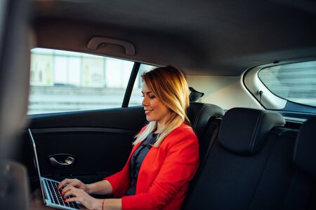 Photo of a young business woman using laptop while sitting in the car.の写真素材