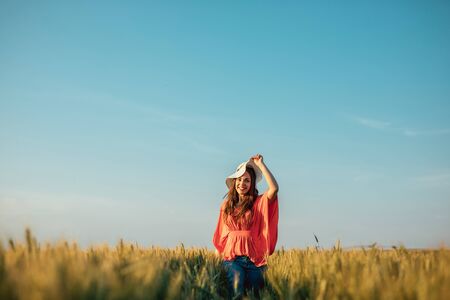 Shot of a young woman taking off her hat in the countryside.の写真素材