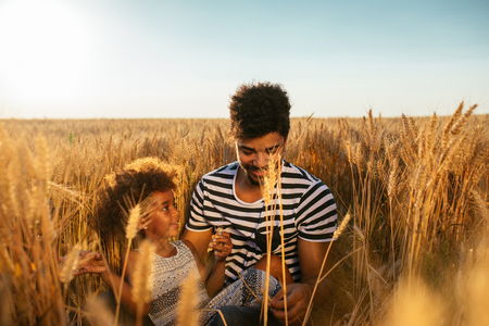 African american dad with his daughter enjoying time out in a wheat field.の写真素材