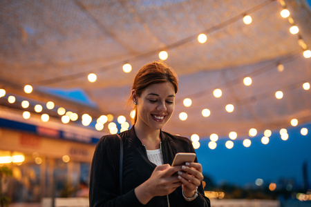 Portrait of a smiling young woman using mobile phone.の写真素材