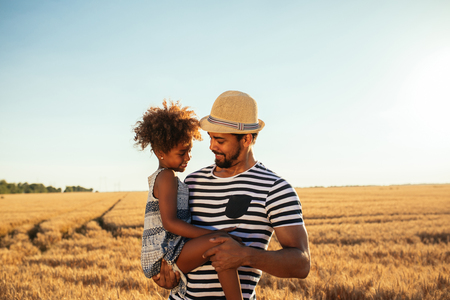 Happy dad and daughter having fun outdoors in a wheat field.の写真素材