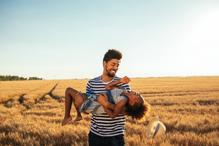 Happy dad and daughter having fun outdoors in a wheat field.の写真素材