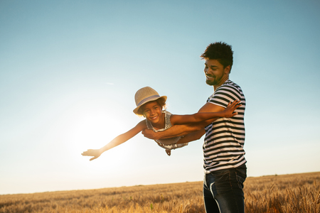 A handsome african american father with his daughter playing in the wheat field.の写真素材