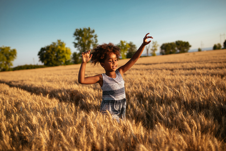 Carefree and playful girl running through the wheat field.の写真素材