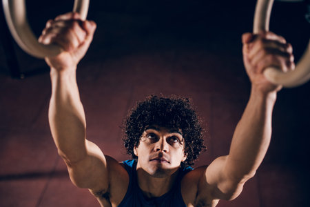 Portrait of athlete man working out on rings in the gym.