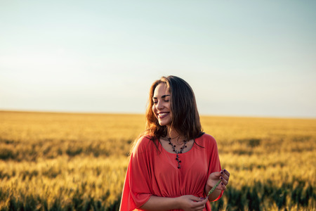 Portrait of a smiling young woman enjoying breathing in the fresh air in the fields.の写真素材