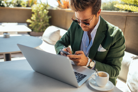Handsome and elegant man multitasking while enjoying a coffee time.の写真素材