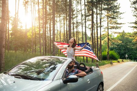 Shot of a young girl holding an american flag while sitting in the car.の写真素材