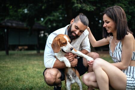 Shot of a smiling young couple having fun playing with a dog outdoors.の写真素材