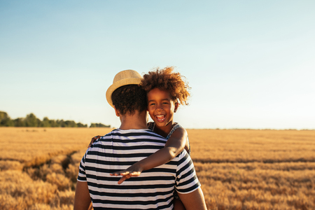 Shot of an african american father and daughter hugging in the fields.の写真素材