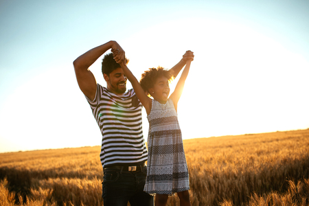 Portrait of an african american father and daughter having fun playing in the fields at sunset.の写真素材