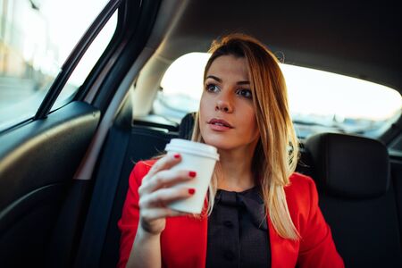 Photo of a smiling business woman in the car drinking coffee.の写真素材