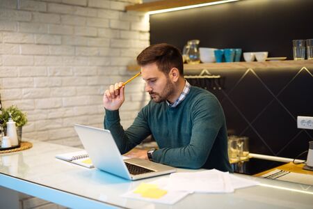 Young successful businessman thinking while using a laptop.の写真素材
