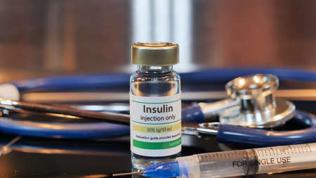 Vial of insulin injection whit syringe and stethoscope stainless steel backgroundの写真素材