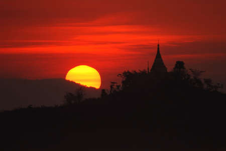View of a silhouetted pagoda in Mrauk U, Myanmar against the rising sun.の写真素材