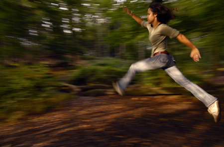 A young woman jumping in a forest with the late afternoon sun on her.の写真素材