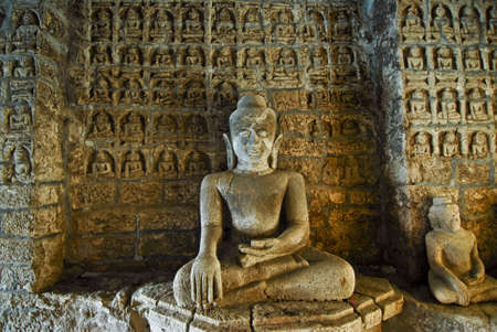 Buddha statue with hundres of bas relief figurines in the back at a temple in Mrauk U, Myanmar (Burma)の写真素材