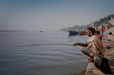 A man fishing at the heavily polluted Ganges river in Varanasi, India.のeditorial素材