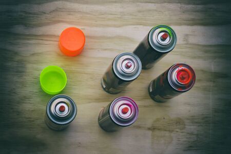 Photograph of some spray paint cans on a wood tableの写真素材