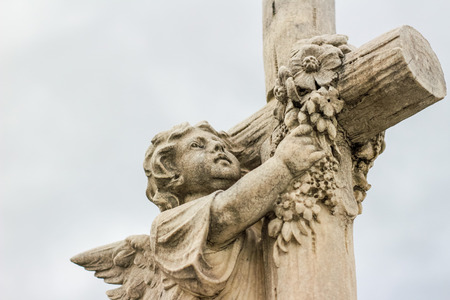 Photograph of an Angel and religious Cross sculpted statueの写真素材