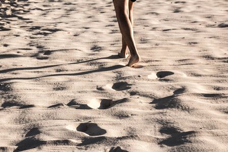 Photoraph of beach sand with a person walking and foot printsの写真素材
