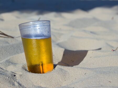 Photograph of a glass of beer on beach sandの写真素材