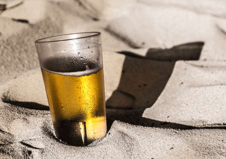 Photograph of a glass of beer on beach sandの写真素材