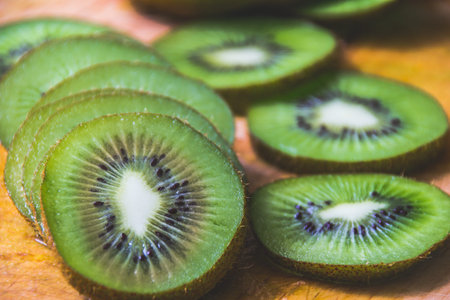 Photogrpah of some green slices of kiwi fruit on wood cutting board