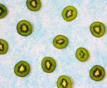Photograph of some green slices of kiwi fruit on light blue backgroundの写真素材