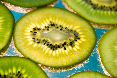 Photograph of some green kiwi fruit slices on lighted glass
