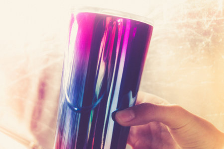 Photograph of a metallic colorful glass and human handの写真素材