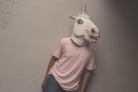 Photograph of a teen with a funny unicorn maskの写真素材
