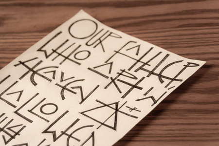 Photograph of a sheet of paper with the Our Father prayer fragment written on it