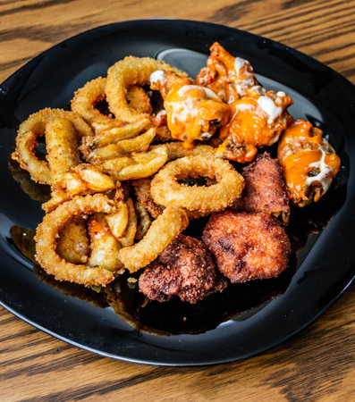 Photograph of a plate of chicken wings with onion rings and criscut friesの写真素材