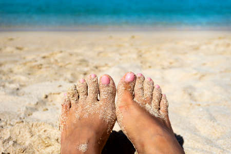 Close up tan barefoot with a little sand on beach backgroundの写真素材