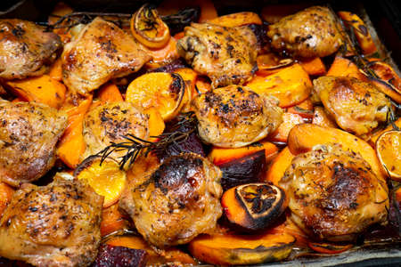 oven Baked chicken legs thighs with sweet potato, oranges and rosemary, top viewの写真素材