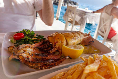 Eating grilled calamari squid in a seafood restautant by the cost in Santorini Oia Amoudi bayの写真素材