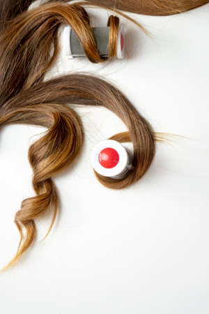 piece of brown curly shiny hair on white isolated background with curler rollerの写真素材