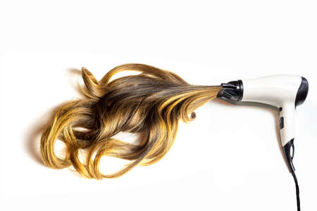 hair dryer blowing brown balayage curvy hair on isolated white backgroundの写真素材