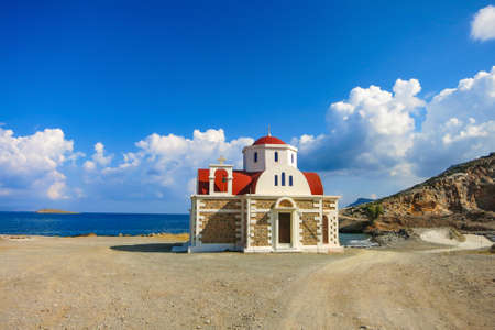 Chapel in Crete greak near Hersonissos by the coast next to the sea with blue cloudy skyの写真素材