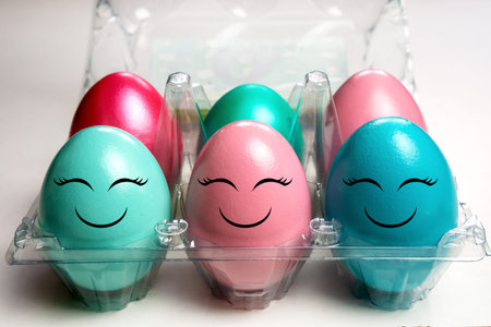 colorful easter eggs in plastic egg case pack with happy emoji faces
