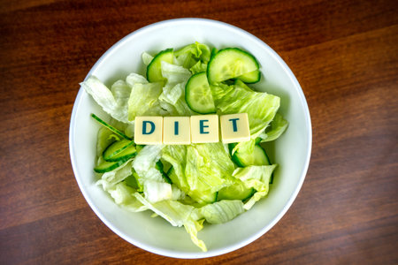 extrem hard diet concept salad in a white plate with lettuce and diet letters on wooden background