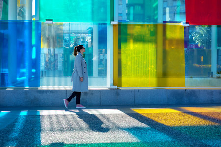 Spain, Malaga - 04.04.2019: Woman walking next to the glass colorful cube Centre Pompidou in Malaga,...